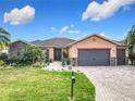 Charming home featuring a well-manicured lawn, brick-paved driveway, two-car garage and stone-accented exterior at 484 Villa Park Rd, Kissimmee, FL 34759