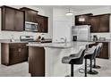 Modern kitchen with stainless steel appliances, granite countertops and dark wood cabinets, and bar stool seating at 7622 Oakmoss Loop, Davenport, FL 33837