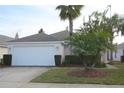 Charming single-story home featuring a well-maintained lawn, two-car garage, and mature tropical landscaping at 991 Lake Berkley Dr, Kissimmee, FL 34746