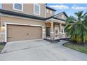 A tan two-story home featuring a garage and front porch with brick pillars, offering curb appeal at 1894 Valley Forge Dr, St Cloud, FL 34769