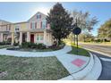 A beautiful townhome with red shutters and a front yard featuring a lovely tree at 10210 Hartford Maroon Rd, Orlando, FL 32827