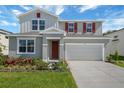 Two-story house with a gray exterior, red shutters, landscaped front yard, and a two car garage at 1111 Olivine Ave, Dundee, FL 33838