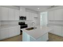 Modern kitchen featuring white cabinets, stainless steel appliances, a quartz island, and wood-look tile flooring at 1111 Olivine Ave, Dundee, FL 33838