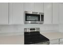 Close-up of new stainless steel oven and microwave, quartz countertops, and sleek white cabinets at 1111 Olivine Ave, Dundee, FL 33838