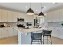 Modern kitchen featuring white cabinets, stainless steel appliances, a center island, and stylish pendant lighting at 1111 Olivine Ave, Dundee, FL 33838