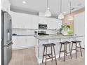 Modern kitchen features white cabinets, stainless steel appliances, an island with seating, and pendant lighting at 1119 Olivine Ave, Dundee, FL 33838