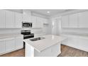 Bright kitchen featuring a large island with sink, white cabinets, stainless steel appliances, and tile floors at 1127 Olivine Ave, Dundee, FL 33838