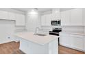 Modern kitchen featuring white cabinets, stainless steel appliances, and a center island with a sink at 1131 Olivine Ave, Dundee, FL 33838