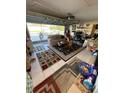 View of cluttered residential garage converted to living space with sofa, desk, and area rugs at 2416 Oak Mill Dr, Kissimmee, FL 34744