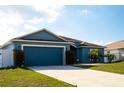 Attractive blue single-Gathering home featuring a well-kept lawn, palm trees, and a two-car garage at 318 Elderberry Ct, Kissimmee, FL 34759