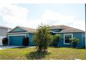 Inviting blue home with well maintained lawn, tropical landscaping, and an attached two car garage at 318 Elderberry Ct, Kissimmee, FL 34759