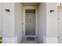 Inviting entryway with a gray front door, decorative welcome mat, and modern outdoor lighting at 408 Danube Dr, Poinciana, FL 34759