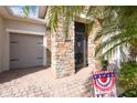 Inviting home front with stone accent wall, brick paver driveway, and lush tropical landscaping at 538 Via Vitale Ct, Kissimmee, FL 34759