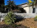 Well-manicured front yard with white picket fence and lush tropical foliage at 9319 Se 173Rd Hyacinth St, The Villages, FL 32162