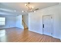 Open living room with modern lighting, wood floors, staircase, and fresh white walls at 1111 Oscar Sq, Celebration, FL 34747