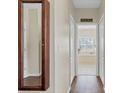 Hallway with wood floors leads to a bathroom featuring a soaking tub beneath a window at 19331 Briercrest Trl, Orlando, FL 32833