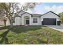 Charming single-Gathering home featuring a dark roof, white exterior, and a two-car garage at 411 Boxwood Dr, Davenport, FL 33837