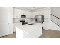 Bright, white kitchen features stainless steel appliances, an island with a sink, and tile floors at 570 Summit River Dr, Apopka, FL 32712