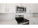 Close-up of kitchen features including stainless steel microwave, electric stove, and quartz countertops at 570 Summit River Dr, Apopka, FL 32712