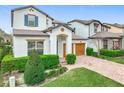 Two-story home featuring a paver driveway, two-car garage, manicured lawn, and green landscaping at 6974 Trellis Vine Loop, Windermere, FL 34786