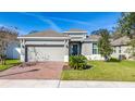 Charming single-Gathering home featuring a well-maintained lawn, brick driveway, and two-car garage at 1097 Hendon Loop, Davenport, FL 33837