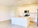 Open-concept kitchen with white cabinets, an island with sink, and stainless steel appliances at 1613 Pelican Dr, Davenport, FL 33896