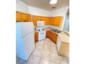 Cozy kitchen featuring wood cabinets, white appliances, and tile flooring for easy maintenance at 19934 Villa Isle # 107, Orlando, FL 32821