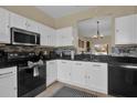 Bright kitchen features white cabinets, black countertops, stainless steel microwave, and mosaic tile backsplash at 2234 Calabria Ave, Davenport, FL 33897