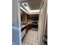 Galley kitchen offers wooden cabinetry, light countertops, and modern black appliances at 2900 S Semoran Blvd # S, Orlando, FL 32822