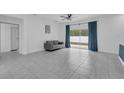 Bright living room features neutral tile flooring and sliding glass doors with curtains at 33 Perch Dr, Kissimmee, FL 34759