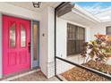 Close-up of a vibrant pink front door, framed by white brick and lush greenery at 3619 Willow Lake Ct, St Cloud, FL 34769