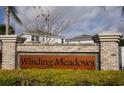 Winding Meadows community sign surrounded by lush shrubbery creates an inviting neighborhood entrance at 3987 Meandering Bay Dr, Apopka, FL 32712