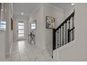 Bright entryway featuring elegant marble floors, modern decor, and staircase with black railing at 718 Whistling Straits Blvd, Davenport, FL 33896