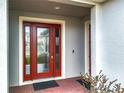 A welcoming red front door with sidelights and brick pavers at 7641 Modica St, Clermont, FL 34714
