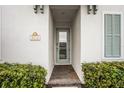 Inviting front entrance of the home with a glass door and lush green bushes either side at 8012 Lost Shaker Ln, Kissimmee, FL 34747