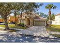 Charming two-story home with tile roof, arched entry, and well-manicured landscaping at 113 Tiger Lily Ct, Davenport, FL 33837