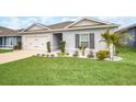 Single-story home boasts green lawn, landscaping, and a two-car garage, offering curb appeal at 1185 Catskill Dr, Haines City, FL 33844