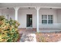 Welcoming front porch with white pillars and railing, leading to an open front door, and adorned with neat landscaping at 318 Rock Springs Dr, Poinciana, FL 34759