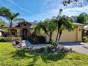Charming home with a two-car garage, a brick driveway, lush landscaping, and mature palm trees in the front yard at 400 Indian Wells Ave, Poinciana, FL 34759