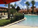 Resort-style pool area with lush landscaping, palm trees, and comfortable lounge chairs at 6153 Metrowest Blvd # 103, Orlando, FL 32835