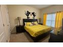 Bedroom with a black headboard, yellow bedding, and bright, natural light at 8974 California Palm Rd, Kissimmee, FL 34747
