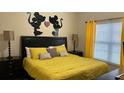 Bedroom with a black headboard, yellow bedding and Mickey Mouse wall decor at 8974 California Palm Rd, Kissimmee, FL 34747
