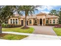 Elegant home featuring a tile roof, arched entryway, three-car garage, landscaped front yard and brick paved driveway at 11856 Vinci Dr, Windermere, FL 34786