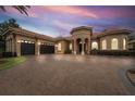 Elegant home featuring a tile roof, arched entryway, three-car garage, landscaped front yard and brick paved driveway at 11856 Vinci Dr, Windermere, FL 34786