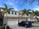 Charming townhome showcasing lush palm trees, brick accents, paved driveway, and attached garage at 1509 Portofino Meadows Blvd, Orlando, FL 32824