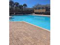 Community pool features refreshing water, brick trim, lounge chairs, safety equipment, and nearby building access at 1510 Chelsea Dr, Davenport, FL 33897