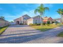 Well-maintained single-story home with a brick driveway, palm tree in the front yard, manicured landscaping, and neutral paint at 153 Cambridge Ave, Davenport, FL 33896