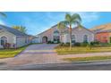 Well-maintained single-story home with a brick driveway and mature palm tree in the front yard, side yard, and neutral paint at 153 Cambridge Ave, Davenport, FL 33896