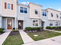 Charming townhouse featuring a modern design with complementary colored stucco and siding, landscaped front yard, and inviting entries at 1800 Tropical Palms Cir, Kissimmee, FL 34747