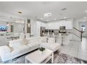 Bright and spacious living room featuring an open floorplan, modern lighting, white L-shaped sofa and access to the kitchen at 1800 Tropical Palms Cir, Kissimmee, FL 34747